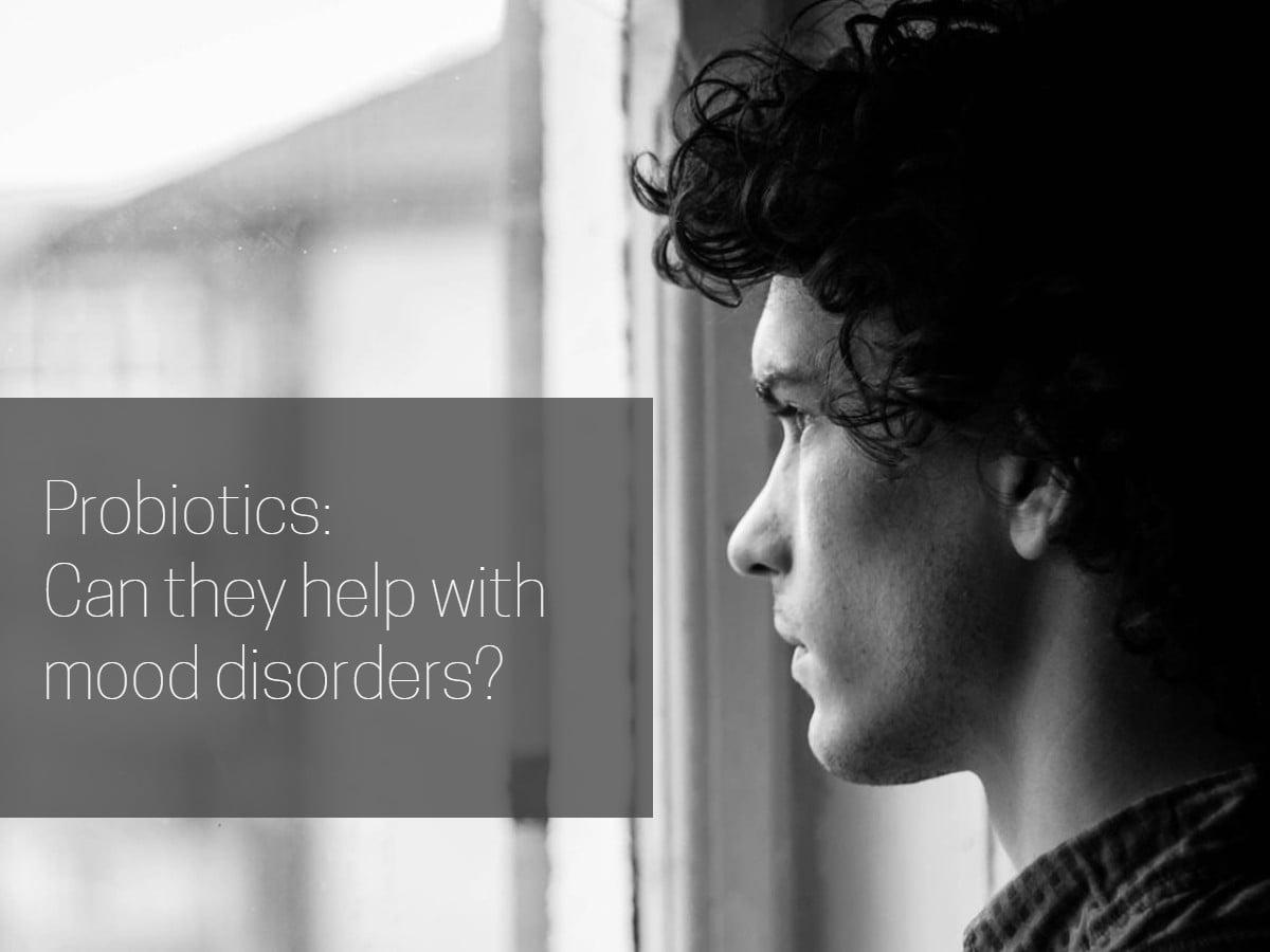 Cover image for article on probiotics and moo disorders with a young man looking out a window in black and white