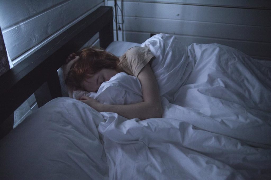 Image of a fatigued woman laying down curled up in blankets