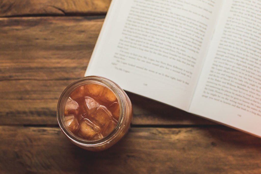 Image of kombucha tea on a wooden table next to a book from above