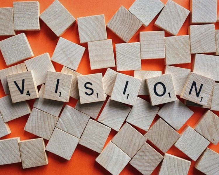 Image of wood blocks against an orange background that spells out 'vision'