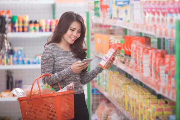 Image of a woman reading a nutrition label in a grocery store