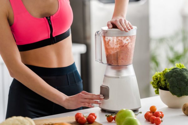 Photo of a woman in athletic wear blending a nutritional smoothie