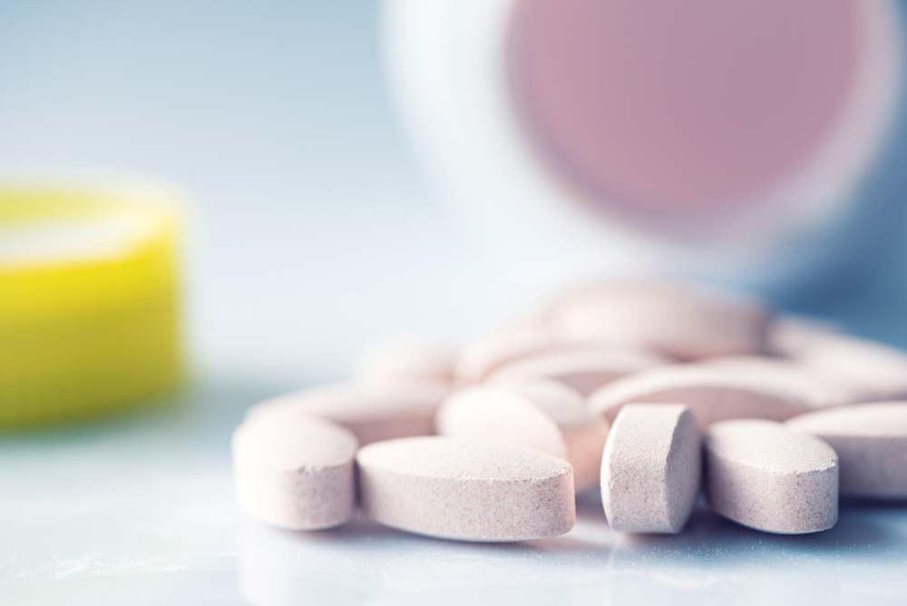 Image of multivitamin supplement pills laid out on a table coming out of a bottle