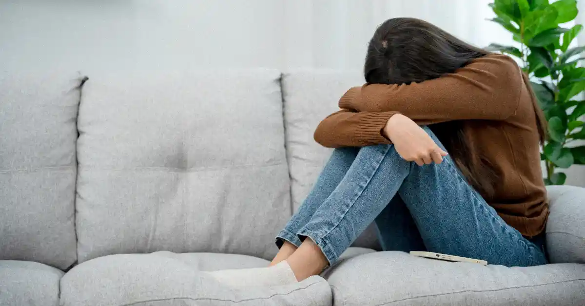 woman looking sad sitting on couch