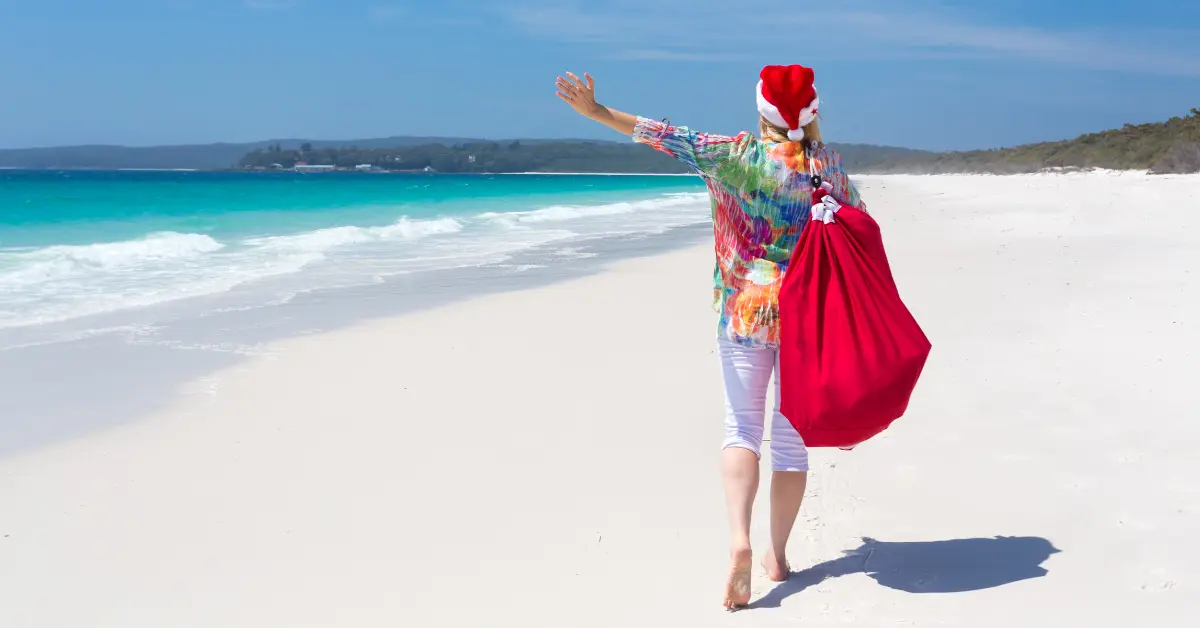 woman on beach with santa bag. holiday travel